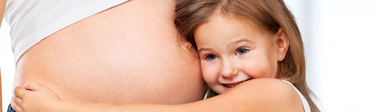 Kind horcht an Bauch von Mutter